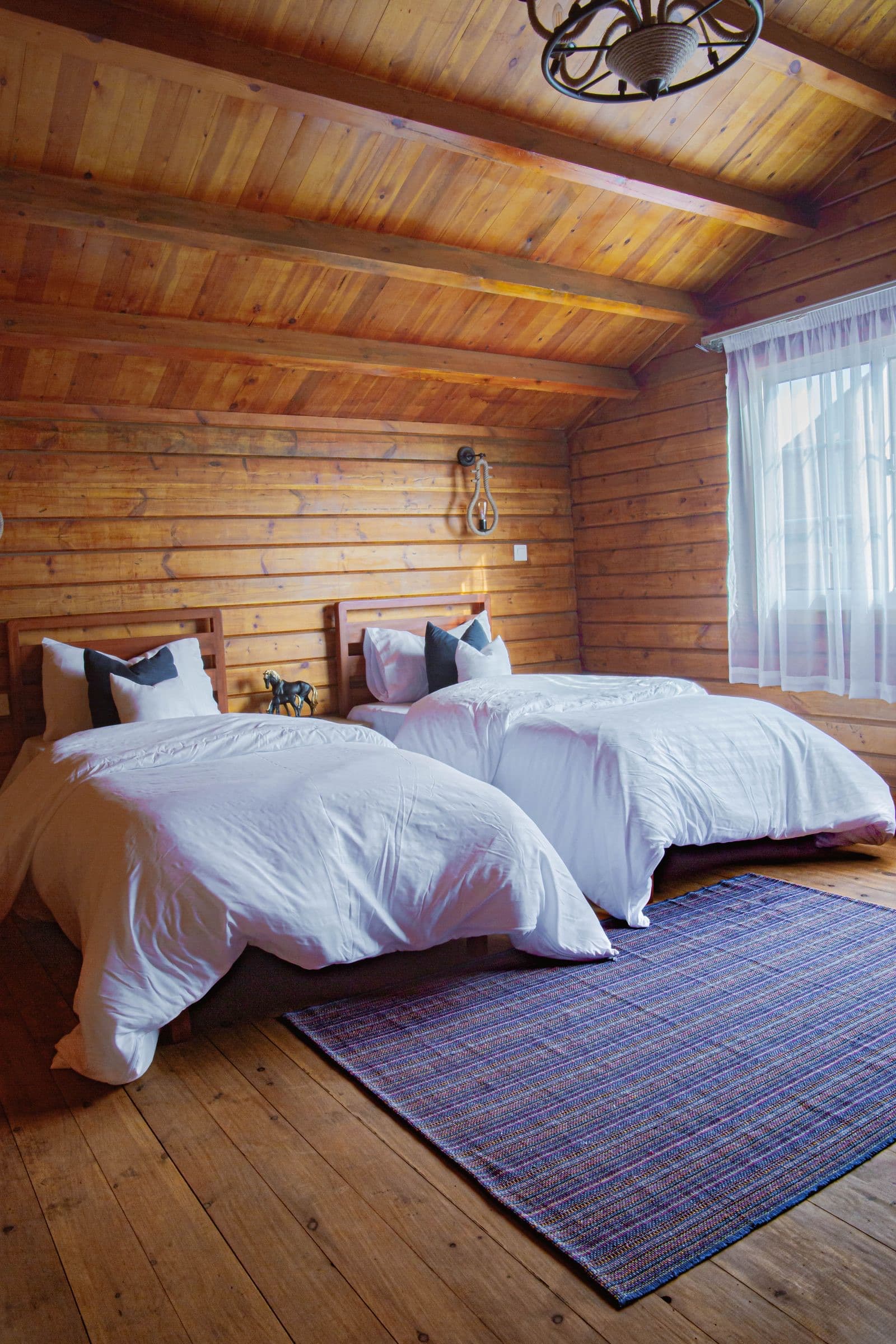 A wood-panelled bedroom with two beds and white linen