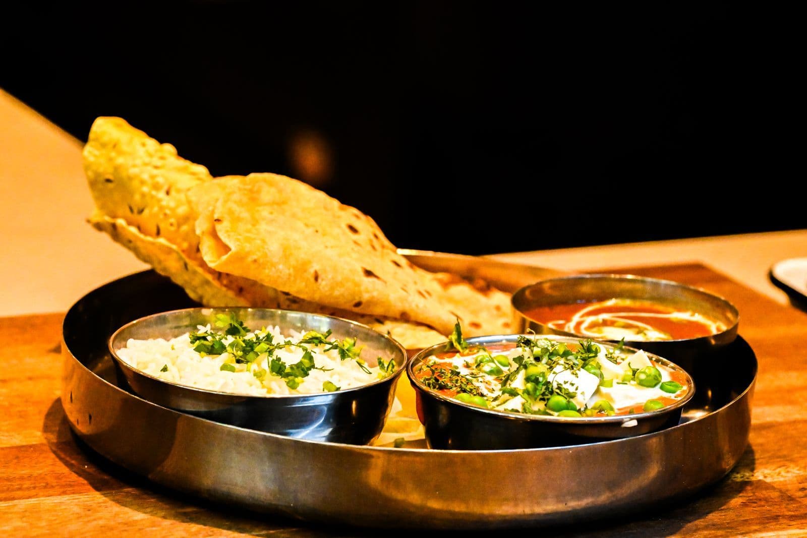 A thali with rice, matar paneer, dal, rotli and papad