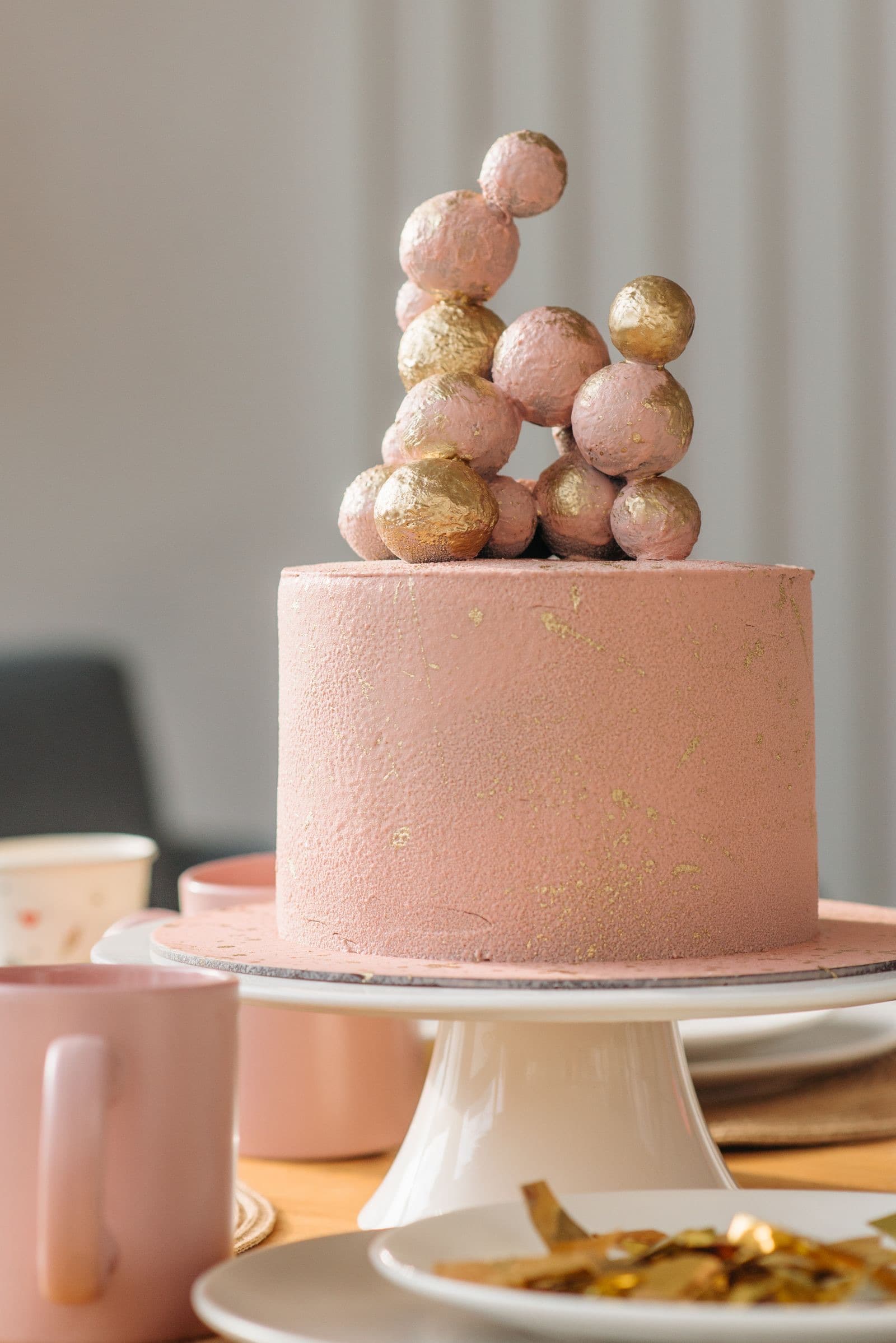 A pink celebration cake topped with gold spheres