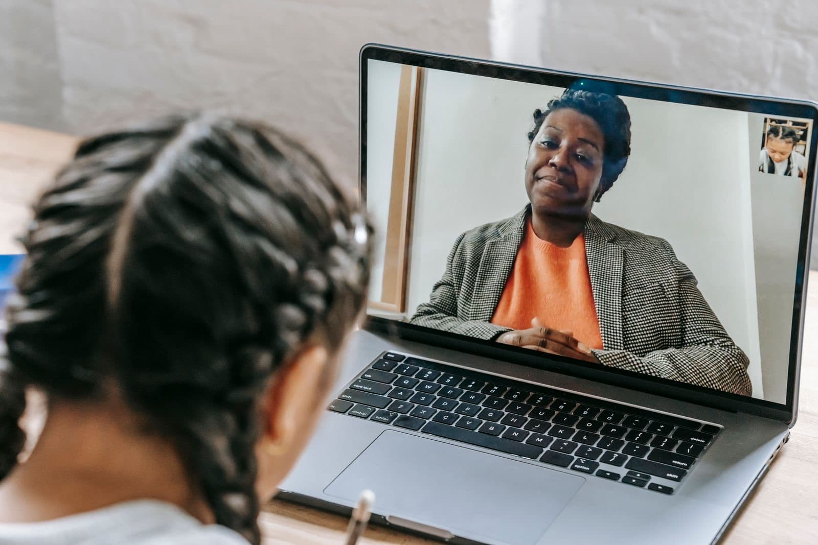 A student in an online lesson with a tutor on a laptop